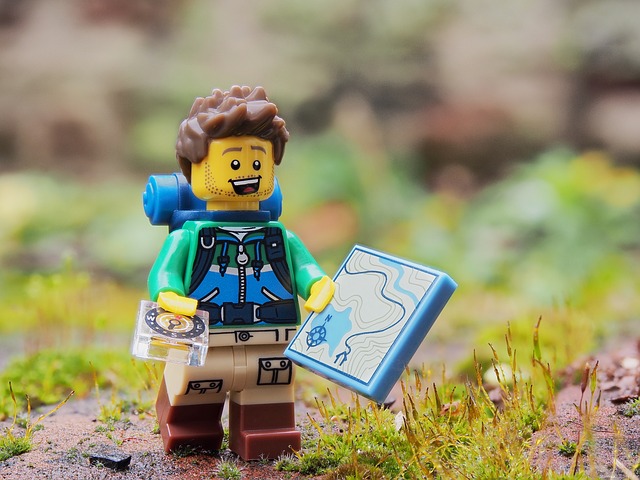 A lego hiker guiding his way with a compass and a map